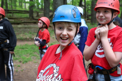 Two children wearing helmets at a ropes course.