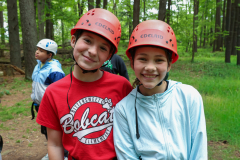 Two children wearing helmets at a camp.