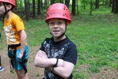 Young boy in red helmet posing for picture at camp.