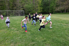 Children running in a field during a game.