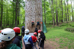 People climbing a rock wall at a camp.