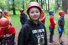 Girl in red helmet posing with group of people wearing helmets and harnesses.
