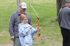 A man and a girl are holding bows in an outdoor setting.