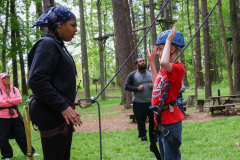 Woman teaching child how to use a fishing rod in a park.