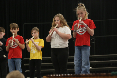 Children playing musical instruments on stage.