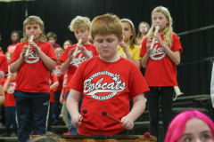 Young boy playing a drum in a school band performance.