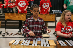 Two children playing musical instruments in a school concert band setting.