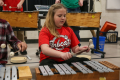 Young girl playing a keyboard in a classroom setting.