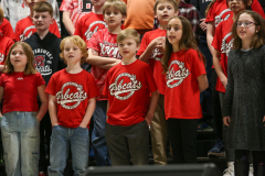 Children in red shirts performing in a school concert.