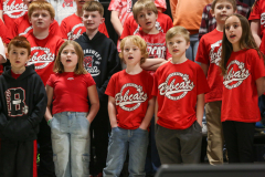 Group of children in red shirts standing on stage at a school concert.