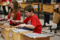 Two children playing musical instruments in a classroom setting.