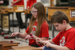 Two children playing musical instruments in a classroom setting.