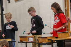 Three children playing instruments in a school concert.