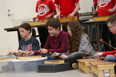 Children playing musical instruments in a classroom setting.