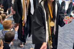 Graduates in caps and gowns walking down a hallway.