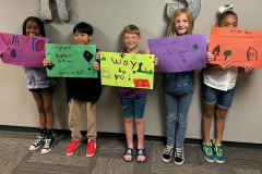 Children holding signs at a parade, celebrating their graduation.