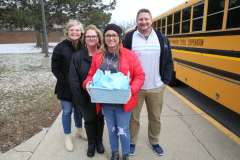 Group of people posing in front of a yellow school bus.