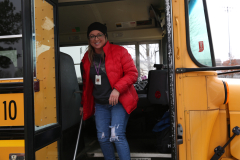Woman in red coat standing on school bus steps.