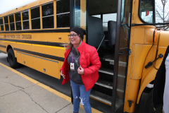 Woman standing next to school bus, smiling at camera.