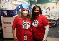 Two women in a classroom, one wearing a mask and the other a Dr. Seuss-themed hat, celebrating Dr. Seuss Day.