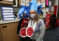Woman and child in classroom celebrating Dr. Seuss Day, both wearing masks and creative costumes inspired by characters from