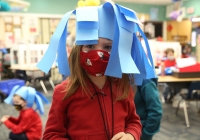 Young girl wearing a Dr. Seuss-themed mask made of blue paper.
