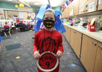 Young boy wearing a face mask in a classroom.