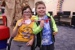 Two young boys proudly displaying their ribbons at a school event.