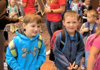 Two young boys in school uniforms posing for a picture on their first day of kindergarten.
