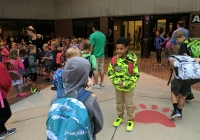Children in front of school building on first day of kindergarten.