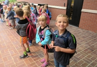 Children standing in front of a building on their first day of school.