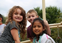Three children on a swing set at a park.