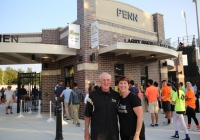 Two people posing in front of a stadium entrance.