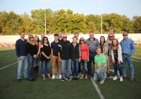 A group of people posing for a team picture on a football field.