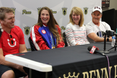 People sitting at a table in front of microphones, with one person holding a sign that says "PENN".