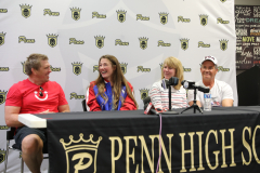 People sitting at a table in front of a banner for PENN HIGH SCHOOL.