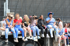 People sitting on a truck during a parade, celebrating the 4th of July.