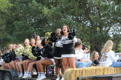 Several cheerleaders on a float celebrating at parade, surrounded by spectators.