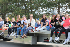 People sitting on a flatbed truck during a parade.