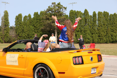 People celebrating in a convertible car during a parade.
