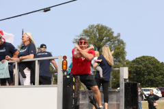 Man in red shirt throwing something to crowd at parade.
