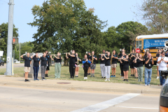 People standing in a line playing instruments on a street corner.
