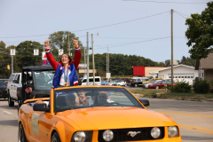 Woman in a convertible car celebrating victory at parade.