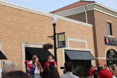 Two people standing on a street corner in front of a brick building during daylight hours.