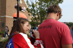 Woman writing on man's back at outdoor event.
