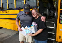 The man is holding a basket of food for the bus driver.